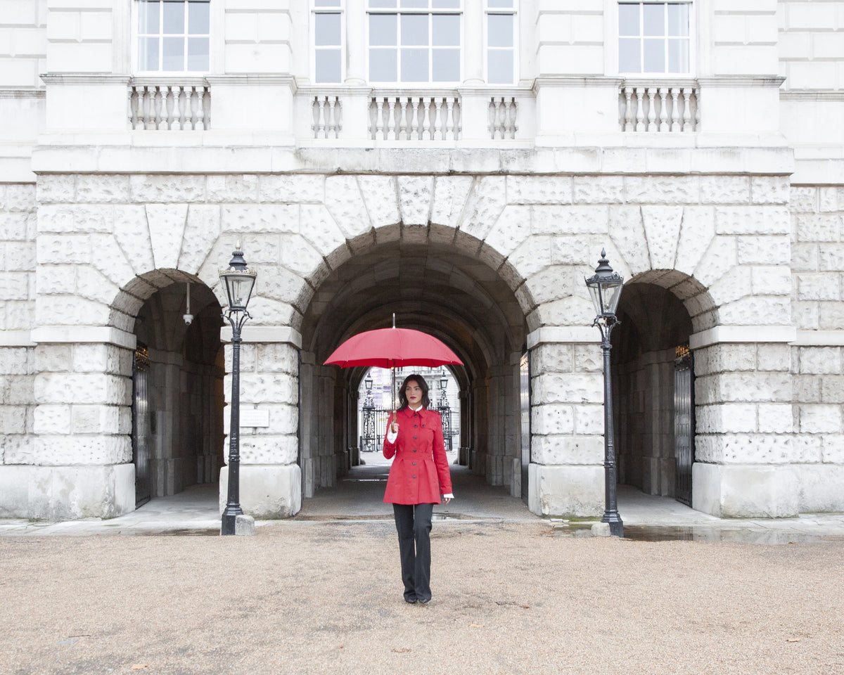 A red Bucklesbury umbrella beneath a Portland stone arch in London